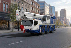 White and blue Tadano mobile crane truck parked on urban street with city buildings in background