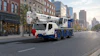 White and blue Tadano mobile crane truck parked on urban street with city buildings in background