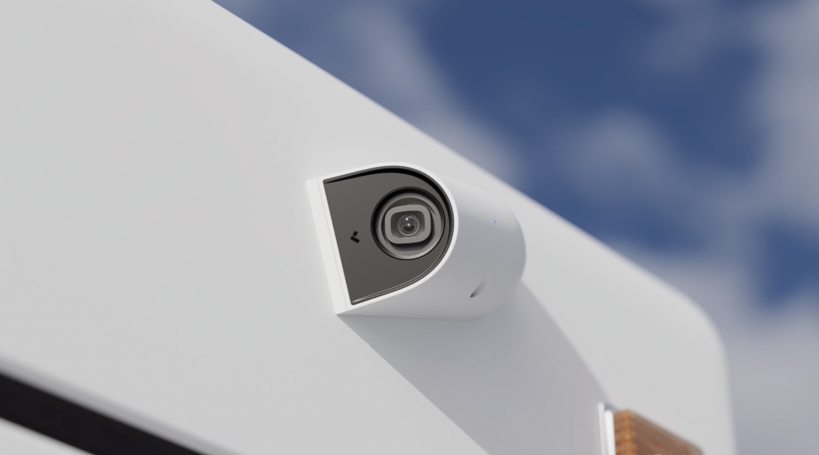 White dome security camera mounted on exterior surface with blue sky background