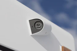 White dome security camera mounted on exterior surface with blue sky background