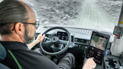 Truck driver navigating snowy mountain road from cabin interior view