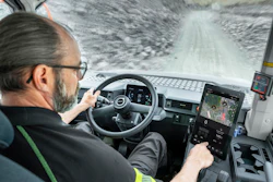 Truck driver navigating snowy mountain road from cabin interior view