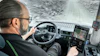 Truck driver navigating snowy mountain road from cabin interior view