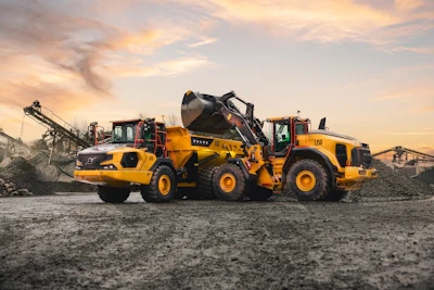 Yellow Volvo construction equipment including wheel loaders and compactors operating at a quarry site during sunset